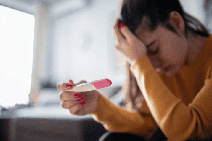 woman holding a pregnancy test and the emotional struggles when trying to conceive